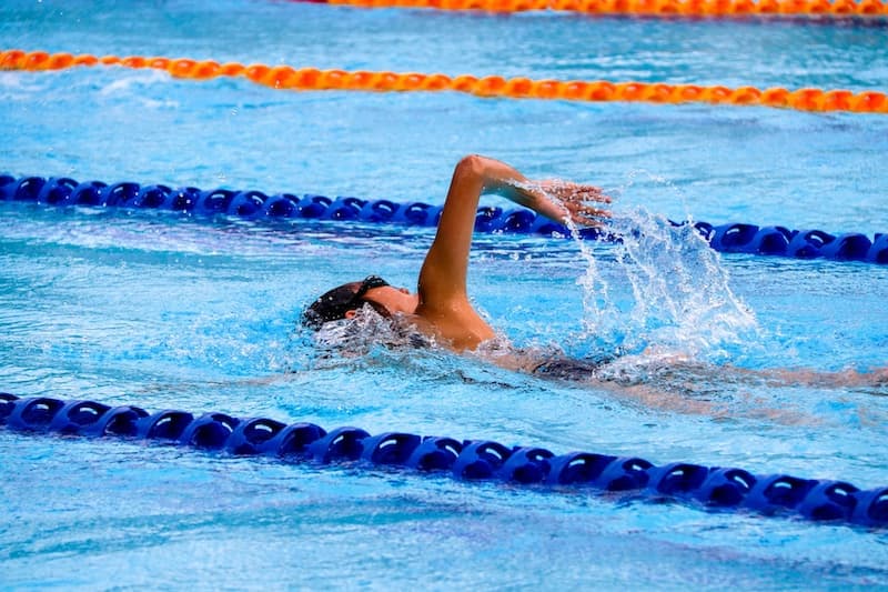 A swimmer doing freestyle in a competition pool